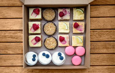 Selection of colorful and delicious cake desserts in box on table, top view.