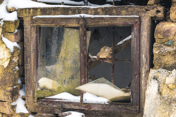 An old broken window with an iron lattice in an abandoned house