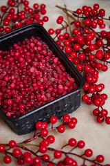 red frozen berries lie in a black dish on a wooden table side view