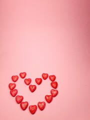 a large heart of small red hearts on a soft pink colored background, copy space. Valentine's Day concept for design.
