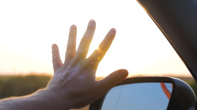 Man hand touching sunlight while traveling by car.