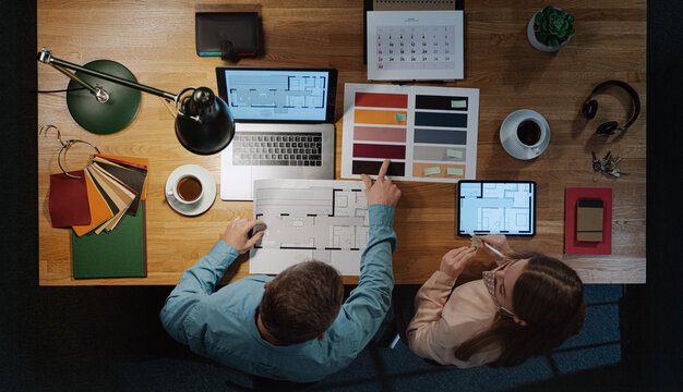 Top view of architects working on computer at desk with paperwork in office, coronavirus concept. - Powered by Adobe