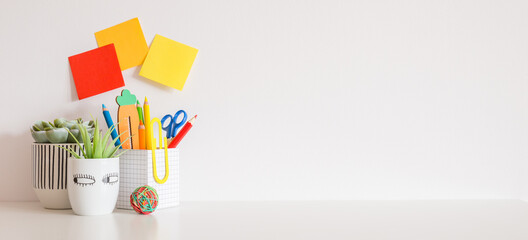 Creative desk with school supplies and white wall for copy space. Banner.	