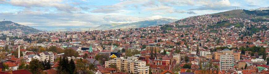 Fototapeta na wymiar Panoramic view over Sarajevo and the surrounding hills under a blue sky with clouds; Bosnia and Herzegovina.
