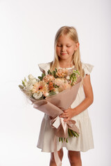 Studio portrait of cute blonde girl in white dress with beautiful gift bouquet, white background, selective focus