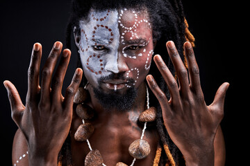 shamanic man stand doing rituals, spreading hands, portrait of black guy with ethnic make-up...