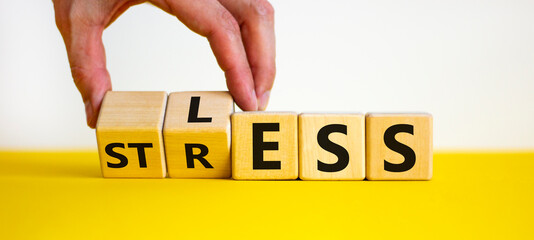 Having less stress or being stress-less. The word 'STRESS' and 'LESS' on wooden cubes. Male hand....