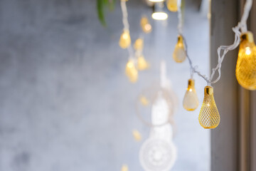 Festive background with hanging luminous garland, stylish decor on cement background, selective focus
