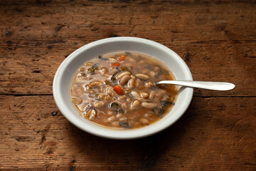 typical dish of Tuscan minestrone on wooden table