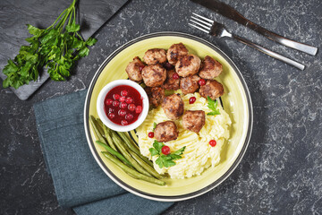 Swedish meatballs with mashed potatoes and green beans on black stone background