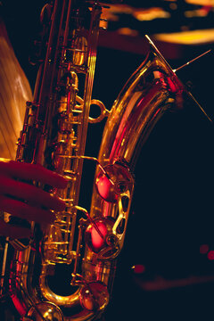 A brass saxophone is played inside of a dark club. 