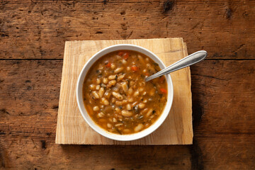typical dish of Tuscan minestrone on wooden table. view from above