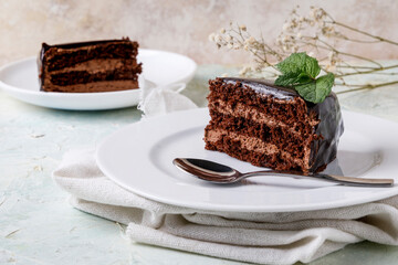 Piece of chocolate cake with mint on white plate