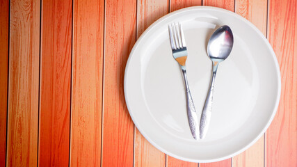Set of empty ceramic dish (plate), spoons and forks isolated on wooden background. Flat lay, Top view. Minimal style.