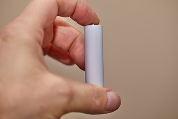 AA Battery Cell held in hand, blank white surface