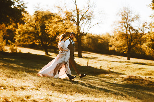 Photo of happy just married couple walking in forest during sunset.