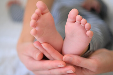 Obraz na płótnie Canvas Tiny baby feet in mom's arms