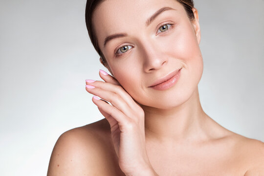 Close up of a beautiful brunette caucasian woman with fresh clean natural skin and soft smile on her face. Neutral, daily make up.