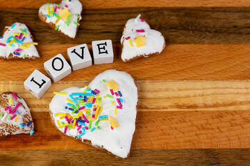 A composition of glazed gingerbreads in the shape of hearts and the word "Love" arranged on a wooden board