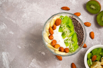 Healthy food concept. Vegan food. Smoothie bowl with chia seeds, nuts, kiwi and banana slices on concrete background with copy space