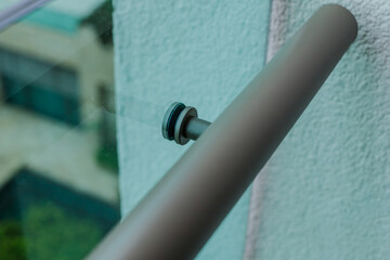 Metal fastening of handrails to balcony glass partition.