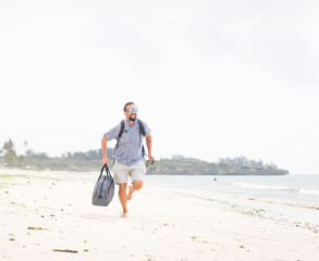 Cheerful adult man with bag having fun on the tropical beach