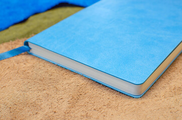 A paper diary in a blue leather cover with a bookmark. On pieces of multi-colored leather.