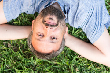 Adult caucasian man lying upside down portrait on grass