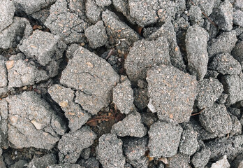 The texture of the destroyed gray asphalt cracked in pieces.