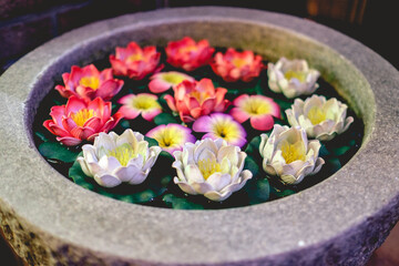 Obraz na płótnie Canvas Stone water fountain with ceramic colorful lotus flowers at temple, Japan