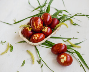 Red Easter eggs dyed with onion peels with a pattern of grass leaves and threads.
White background.
Traditions and Christianity.