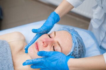 Obraz na płótnie Canvas Spa procedure. Facial massage and spreading cream. Cosmetic skin care
