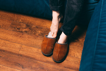 Photo of woman wearing slippers over wooden floor background.