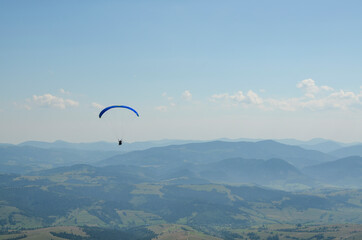 Paraglider flies in the sky over the mountains on a bright sunny day. Paragliding in the sky. Extreme sport.