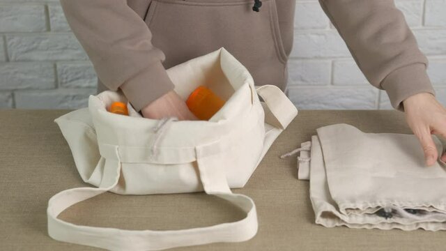Woman with eco shoppers. A woman puts reusable eco-friendly shopping bags into a cotton bag.
