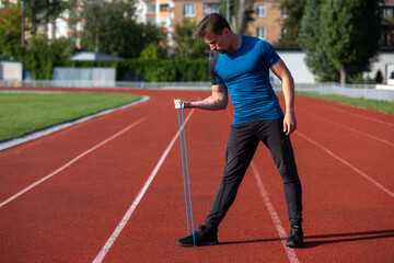 Obraz premium Sporty guy having workout with rubber band outside