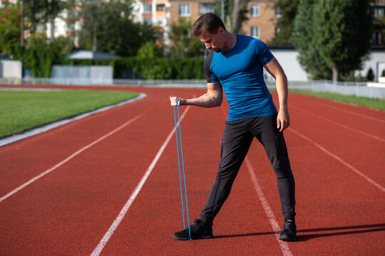 Sporty Guy Having Workout With Rubber Band Outside