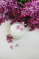 Lilac flowers on the table and in a glass of milk. White background. Free space for an inscription.