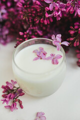 Lilac flowers on the table and in a glass of milk. White background. Free space for an inscription.