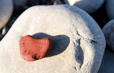 Red stone heart among river or sea pebble stones, Valentine's Day, perfect love