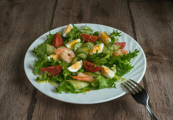 Green salad with shrimps, quail eggs, cucumber and tomato. Healthy breakfast with herbs, shrimps and eggs
