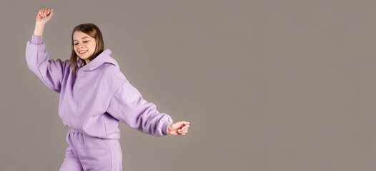 Woman in purple sweetshot dancing with inspired face expression. Active young woman in casual outfit having fun indoor.