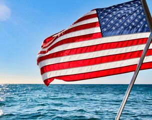The American flag flying on a sunny day with blue ocean and blue skies in background
