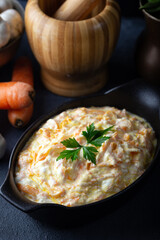 Carrot tarator in ceramic bowl with vegetable on dark background. Fresh carrot salad with garlic yogurt in bowl.