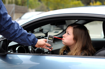 Young female driver during test for alcohol content with breathalyzer, do not drink and drive concept