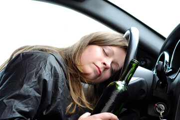 Close up portrait of a beautiful woman lying asleep on the steering wheel drunk after drinking alcohol, do not drink and drive concept