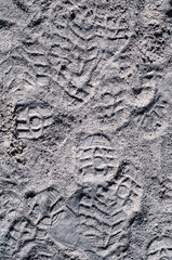 Sand on beach, many footprints in sand, textured surface, vertical photography, natural material, outdoors close-up