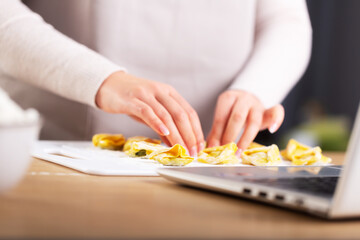 Obraz na płótnie Canvas Woman preparing ravioli and watching virtual culinary master class