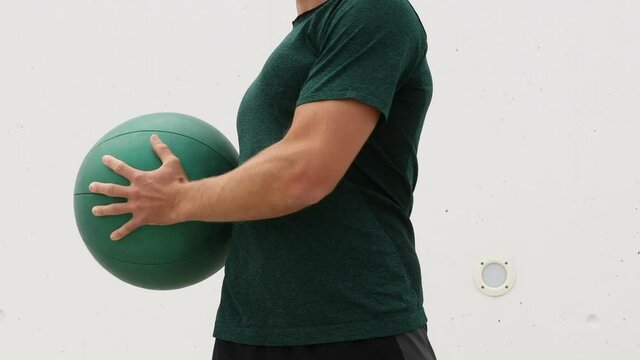 Medicine ball exercises - standing rotation side to side aka standing russian twist. Fit male athlete showing strength training exercises using medicine ball.