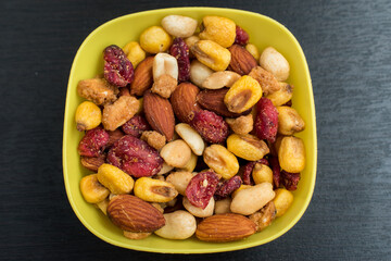 Some peanuts, raisins and nuts in a pot on a dark wooden table 